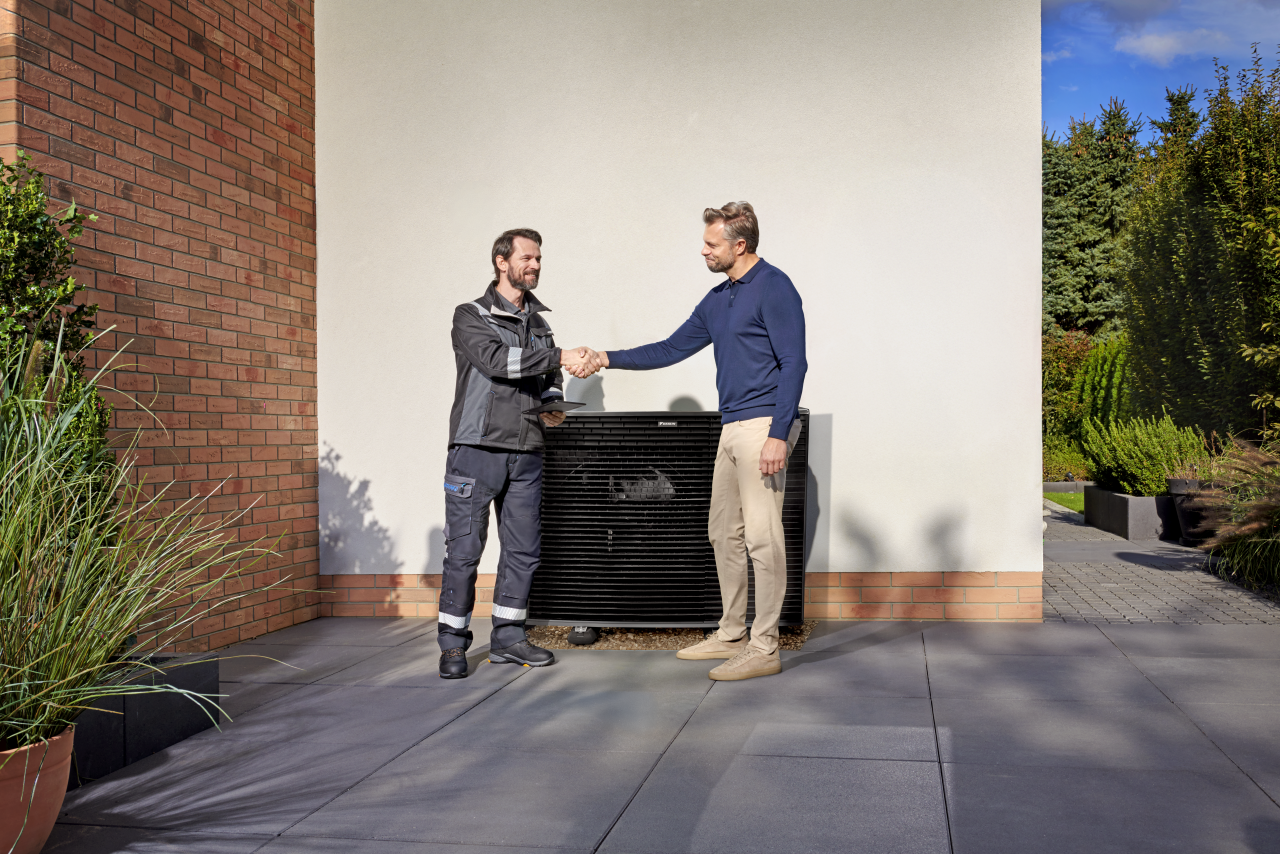 Montuotojas, spaudžiantis rankas su klientu priešais „Daikin Altherma“ lauko įrenginį